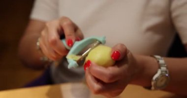 Güzel manikürlü bir kız patates soyar. Yüksek kaliteli video