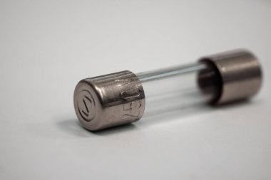Silindirik cam fünyeye yakın çekim, iki ucunda metal kapaklar var, pürüzsüz bir yüzeye yerleştirilmiş. Bu resim ince elektronik bileşen detaylarını, yansıtıcı yüzeyleri ve hassas mühendisliği vurgular..
