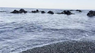 Sakin ve huzurlu bir sahil videosu, yumuşak, doğal gün ışığı altında kıyıya vuran tembel dalgaların yumuşak ritmini yakalar. Huzurlu sahne, suyun karayla buluşmasının rahatlatıcı tekrarıyla meditasyon atmosferini yaratıyor.