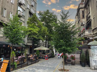 Belgrad, Sırbistan - 18 Mayıs 2022: Tarihi bir bölgede rahat bir kaldırım taşı sokak köşesi. İnsanlar bulutlu bir gökyüzünün altında gelişigüzel yürüyüp şehrin göbeğindeki günlük yaşamı yakalıyorlar..