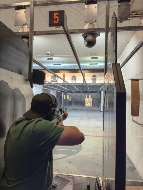 Bir adam, 5 numaralı kulvarın altındaki özel bir bölmede duran bir atış poligonuna tüfek doğrultuyor. Tesis teçhizatlı kameralar ve güvenli bir çevre ile donatılmıştır..