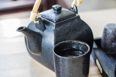 Bambu saplı siyah seramik çaydanlık ve Asya tarzı bardak.