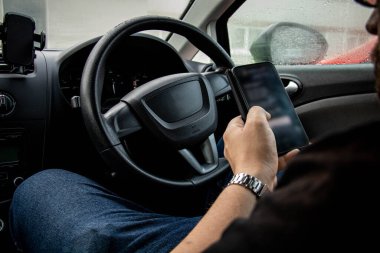 Arabada otururken telefonu elinde tutan adam.