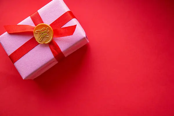 Kırmızı arka planda kırmızı kurdeleli pembe hediyeler.