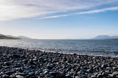 Güneşin arkadan aydınlattığı kayalık bir sahil. Sağ tarafta, körfezi görebilirsiniz.
