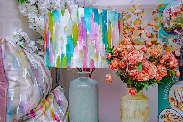 Parlak renkli bir dükkan penceresi, lambası, minderleri ve buketi var.