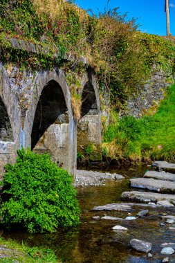 Küçük bir turistik bölgede eski bir köprü sağ tarafında taş basamakları olan Gurteen.
