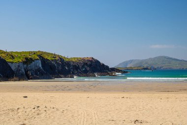 Cow Strand, West Cork 'un en iyi kumsalları ve ufukta bir dağ, uçurumun sol tarafında Cloddagh, Sherkin Adası, Co.