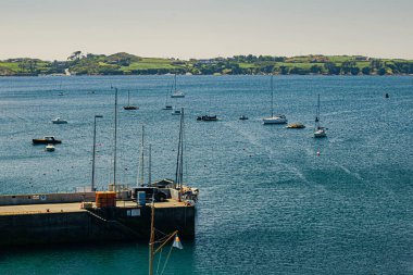 Baltimore İskelesi, İrlanda, denizde yelkenliler, üzerinde evler olan kıyı arka planda görünür.