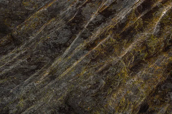 Sarı-turuncu damarları olan kayalık bir şekil.