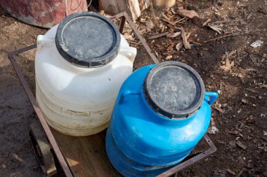 Kirli plastik teneke kutular, taşra bahçesindeki bir arabada su dolu.
