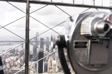 Görüntü, şehrin çarpıcı bir görüntüsünü ön planda madeni para kullanan bir izleyiciyle yüksek bir bakış açısından yakalıyor. Şehir, sayısız gökdelen ve binalarla genişliyor..