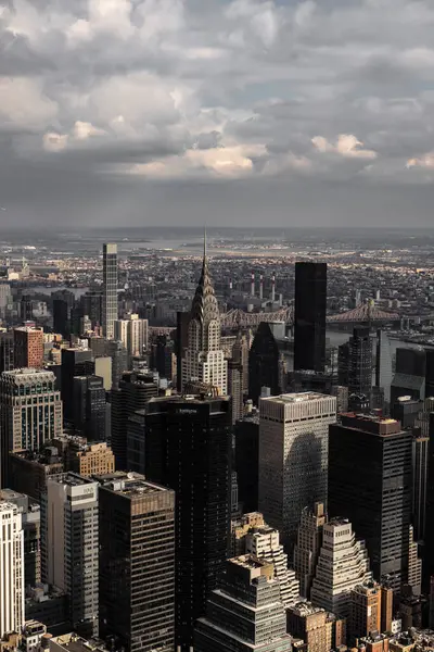 Çok sayıda yüksek binası ve bulutlu gökyüzü olan bir şehir manzarası. Görüntü, yoğun gökdelenler kümesiyle şehir hayatının özünü yakalıyor..