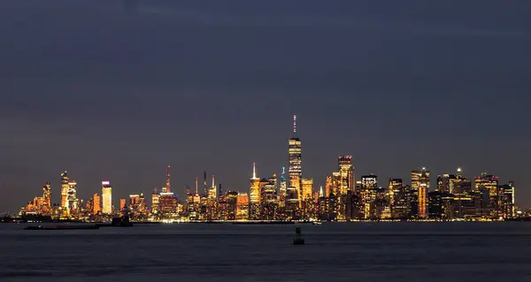 New York şehri gökdelenleri bir su kütlesi üzerinde parlayan sayısız aydınlatma ile geceleri parlıyor. Manzara canlı şehir manzarasını yakalıyor..