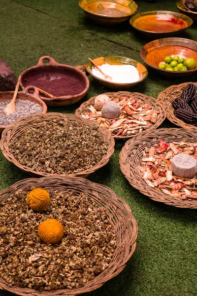 Yeşil bir yüzey üzerinde hasır sepet ve kâselerde dizilmiş geleneksel bitki ve baharat koleksiyonu..