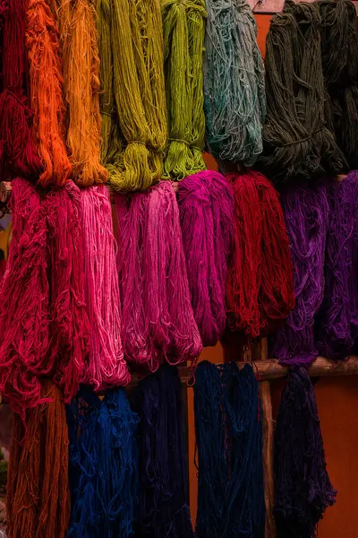 Görüntü, ahşap bir askıda düzgünce dizilmiş çarpıcı renkli iplikler sergiliyor. Canlı renkler parlak pembe ve morlardan koyu mavi ve yeşilliklere kadar değişiyor..