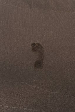 Kumsaldaki kumda yalnız bir ayak izi. Yakınlarda başka insan olduğuna dair bir iz yok. Görüntü yalnızlık ve sükuneti yakalar..