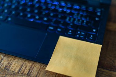 A yellow sticky note is placed on the bottom of a laptop keyboard. The note could be a reminder, a to-do list, or a message to the user clipart