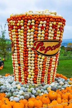 Üzerinde patlamış mısır yazan büyük bir balkabağı kabağı kabağı. Konteynır çeşitli renkli balkabaklarıyla dolu.