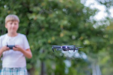 Uzaktan kumandalı bir ergen. Çocuk evin bahçesindeki oyuncak bir dronu kontrol ediyor..