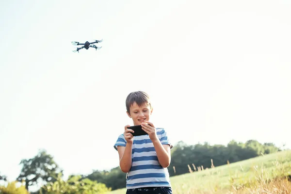 child watches the video on the smartphone from the drone\'s camera. dark gray drone quadcopter with digital camera and sensors flying