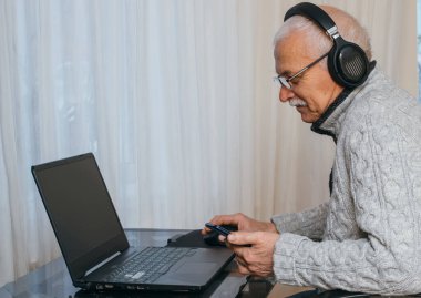 Çevrimiçi eğitim, uzaktan çalışma, evde eğitim. İnternette öğretmenlik yapan gri saçlı, yaşlı ve yakışıklı bir adamın portresi..