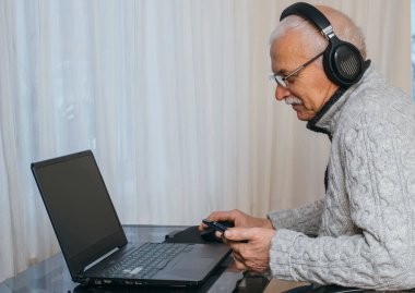 Çevrimiçi eğitim, uzaktan çalışma, evde eğitim. İnternette öğretmenlik yapan gri saçlı, yaşlı ve yakışıklı bir adamın portresi..