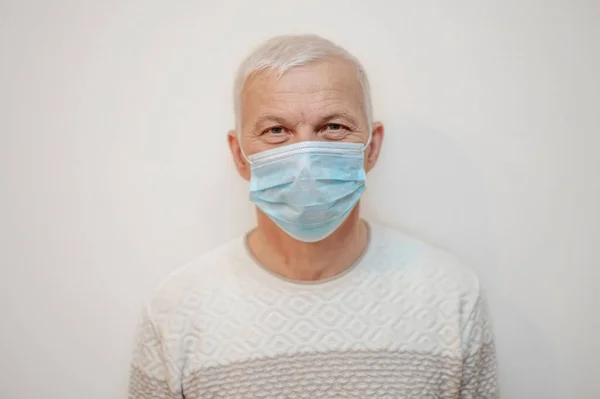 Elderly man in protective medical mask isolate in white. Coronavirus elderly advice. Safety old men. Transmission of virus through touch. Copy space