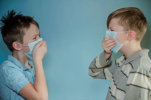 Two children cough, holding hands on faces. Children in protective medical masks communicate without fulfilling conditions of quarantine coronavirus.