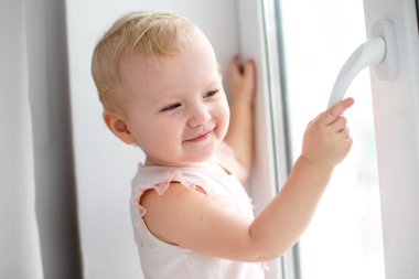 Kapalı pencereler için önlemler. Çocuklar için pencereden düşme tehlikesi uyarısı. Bir çocuk kilidi olmayan bir pencere kuşağının sapını kırar.