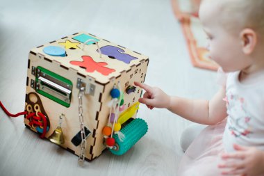 Güzel Motor Yetenekleri için Montessori Duyusal Oyuncak. Bebek bir bulmaca oyununda saat üzerinde küçük bir kalem göstererek sayıları öğreniyor.