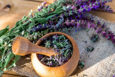 Yazın Avrupa 'nın ekolojik açıdan temiz bir bölgesindeki bir çayırda toplanan kurumuş adaçayı çiçekleriyle dolu ahşap havan topu. Alternatif tıp