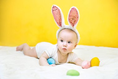 Paskalya konsepti. Tavşan şapkalı küçük kız. Çocuk bir Paskalya yumurtası tutuyor. Komik çocuk yalan söyler ve çerçeveye bakar