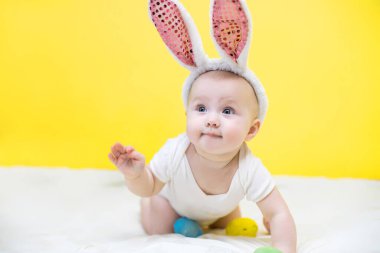 Paskalya konsepti. Tavşan şapkalı küçük kız. Çocuk bir Paskalya yumurtası tutuyor. Komik çocuk yalan söyler ve çerçeveye bakar