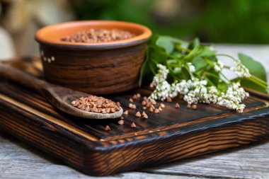 Karabuğday tohumları yakın plan. Ahşap bir masanın tepesinde soyulmuş tahıllar. Yaz mutfağında bir buket karabuğdayla hayat..