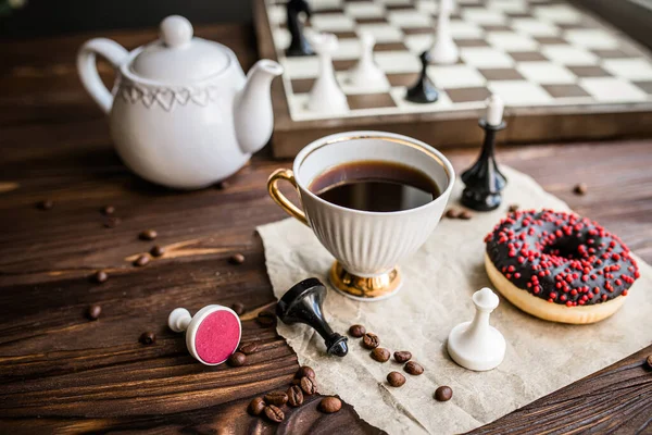 Tea break with board games. Coffee cup with fresh coffee and snacked donat