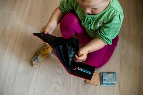little girl takes money out of purse. Children and finances. Spending on children. Fallen out of purse hryvnia, Ukrainian banknotes. Financial crisis during coronavirus in Ukraine