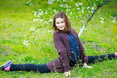 Çocuk haçın ipine oturdu. Bir kız bahar parkında eğleniyor.