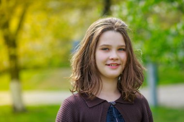 Baharda kiraz çiçeklerinin arasında güzel bir kız. Kahverengi saçlı ve yeşil gözlü bir kızın portresi..