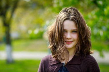 Baharda kiraz çiçeklerinin arasında güzel bir kız. Kahverengi saçlı ve yeşil gözlü bir kızın portresi..