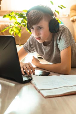 Çocuk dizüstü bilgisayarın, ders kitabının ve ödev için bir iş defterinin yanında yatıyor. Çocuk internette online yayın dersleri izliyor. e-öğrenme, uzaktan eğitim İnternet konsepti.