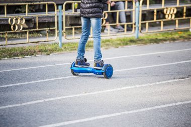Şehrin stadyumunda mavi jimnastik tahtasına binen yırtık kotlu bir kızın bacakları. Aktif yaşam tarzı. Spor için kullanışlı aletler. Beyaz uçan kaykaylı biri. Elektrikli hiroskoper sürücüsü. Kendini dengeleyen iki tekerlekli sörf tahtası ya da uçan scooter. seçili