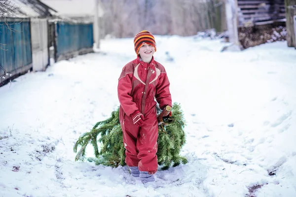 마젠타 작업복을 아이가 크리스마스 트리를 가지고 점프수트를 도로를 속에서 크리스마스 — 스톡 사진