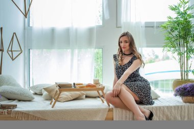 Güzel bir kız servis masasının yanında hafif bir kahvaltıyla oturuyor. Sevgililer Günü için yatakta kahvaltı. Bir kadınla ilgilenmek.