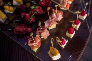 Kanepe, kahverengi tepside kanepe yatağı. Peynir, et, şiş çilek parçaları..