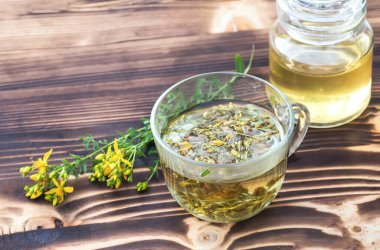 Şeffaf bir fincan dolusu taze Hypericum sarı çiçekli St. John otlu içecek. Bahar balı kavanozu. Alternatif Tıp ve Homeopatik İlaçlar için şifalı bitkiler