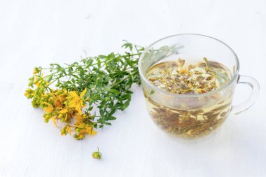 Şeffaf bir fincan dolusu taze Hypericum sarı çiçekli St. John otlu içecek. Bahar balı kavanozu. Alternatif Tıp ve Homeopatik İlaçlar için şifalı bitkiler