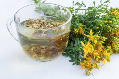 Şeffaf bir fincan dolusu taze Hypericum sarı çiçekli St. John otlu içecek. Bahar balı kavanozu. Alternatif Tıp ve Homeopatik İlaçlar için şifalı bitkiler