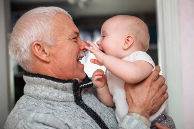 Yeni doğmuş bir bebek yaşlı büyükbabanın burnuna dokunur. Yaşlı bir adam torunuyla eğleniyor. Mutlu nesiller. Aile hayatı