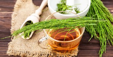 Atkuyruğuyla içeceği iyileştiriyor. Tahta bir masada bir fincan ve kurumuş at kuyruğu otu.